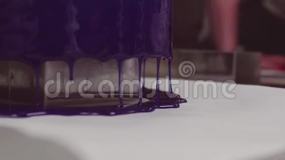 在厨房餐桌上蓝镜釉上的糖霜滴在蛋糕上视频的预览图
