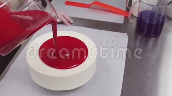 糖果师从量杯中倒入红镜釉上的蛋糕视频的预览图