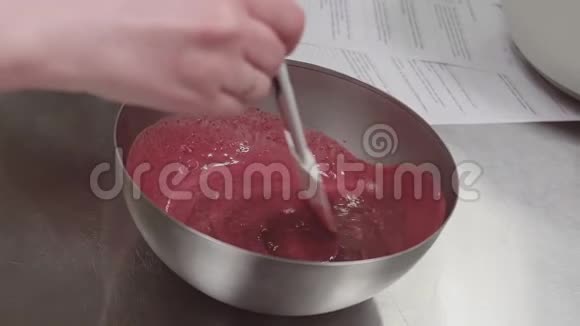 糕点厨师用手搅拌混合碗中的红色浆果果脯视频的预览图