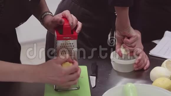 穿围裙的妇女在厨房餐桌上用烤架和带柠檬的榨汁机视频的预览图