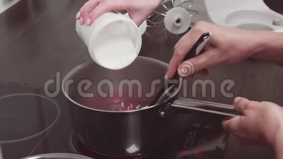 女性用手将糖粉放入锅中放入炖浆果和水果视频的预览图