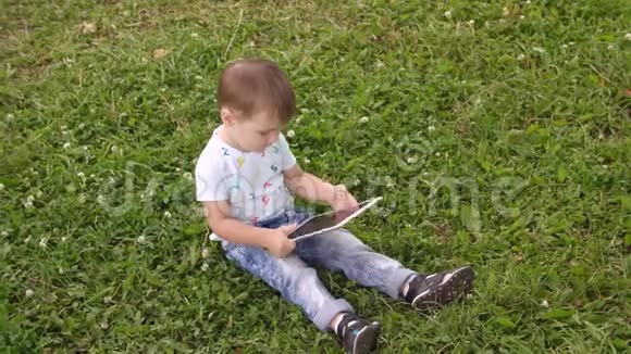 小男孩在公园外面用智能手机平板电脑视频的预览图