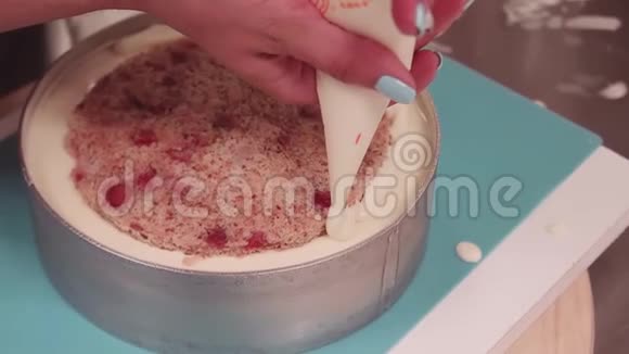 女性糖果师用手将奶油捏在烤制的蛋糕上视频的预览图