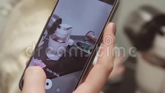 智能手机拍摄作为混合机在厨房工作搅拌红色奶油视频的预览图