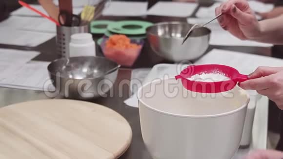女性糕点师将面粉通过筛子筛入搅拌碗中视频的预览图