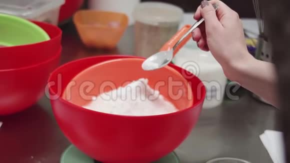 女糕点厨师用手将烤粉勺放入面粉搅拌筛中视频的预览图