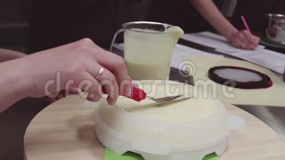 女士糕点厨师手使用糖霜铲在奶油上的菜肴形式在转盘视频的预览图