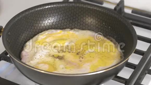在煤气炉上的煎锅里用香肠准备炒鸡蛋视频的预览图