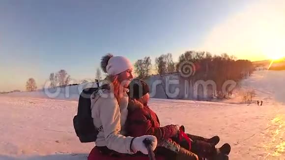幸福的家庭乘坐和微笑的雪管在雪道上慢动作冬天的雪景户外运动日落视频的预览图