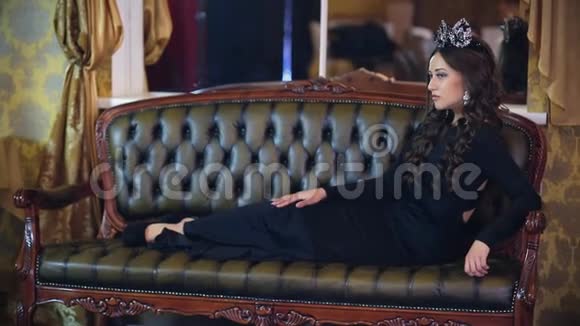 一个美丽的女孩穿着一件长裙化妆和皇冠在经典的室内为摄影师摆姿势视频的预览图