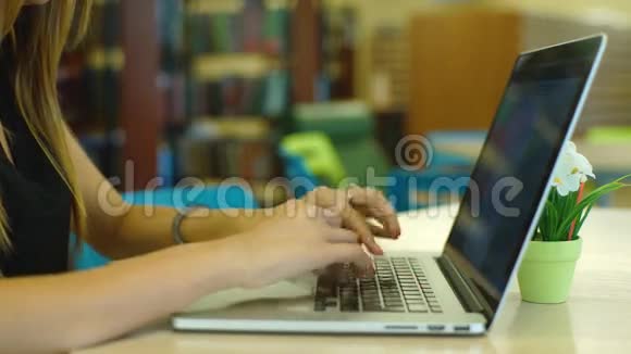 坐在图书馆楼梯上并使用便携式计算机的年轻女学生的特写视频的预览图