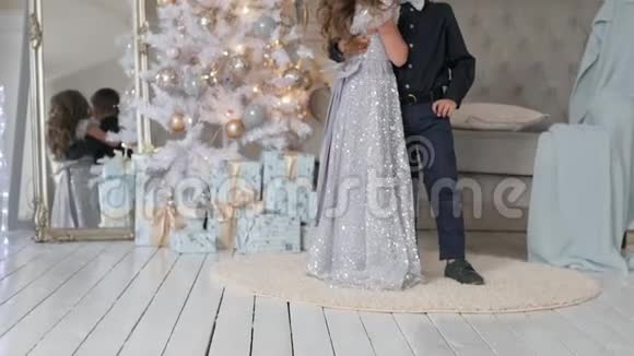男孩和女孩在圣诞树背景上特写穿着漂亮衣服的孩子视频的预览图
