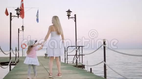 母亲和女儿在夕阳下的木墩上散步视频的预览图