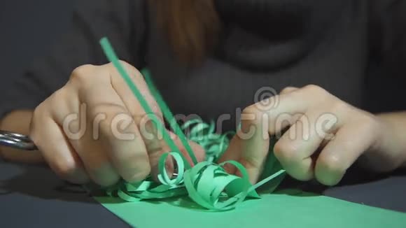 女性的手轻轻地卷曲薄薄的绿色纸与金属剪刀视频的预览图