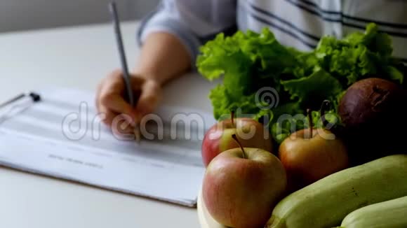 女人在满桌的水果和蔬菜上写饮食计划视频的预览图