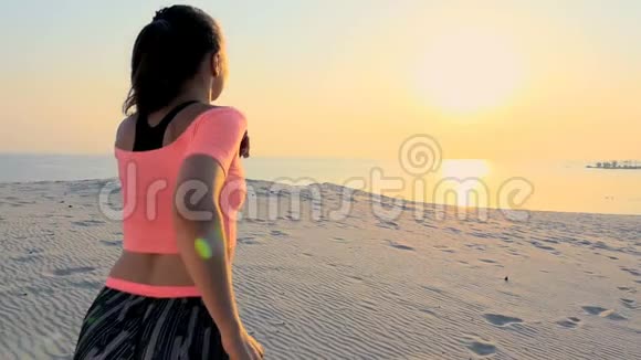 健康年轻的运动美女沿着沙滩奔跑在海滩上在夏天走向太阳在日出视频的预览图