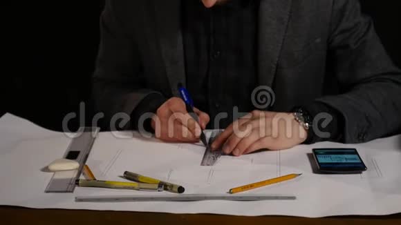 人的建筑师用铅笔在办公桌上的一张大纸上画一个平面图图形设计几何形状黑色视频的预览图
