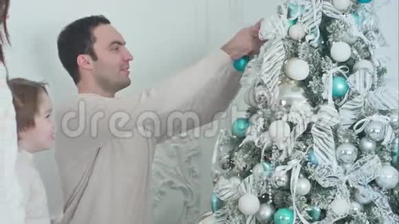 快乐的父母和他们的儿子在客厅装饰圣诞树视频的预览图