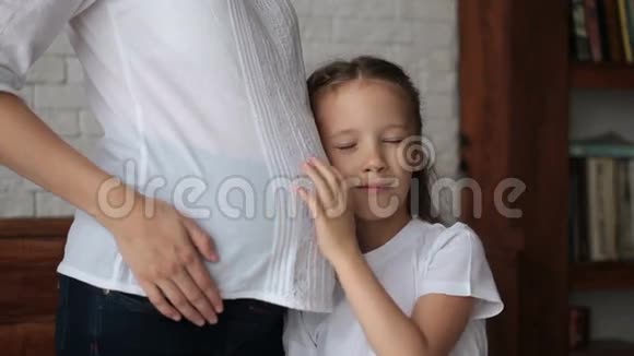 可爱的小女孩靠近她怀孕母亲的肚子视频的预览图