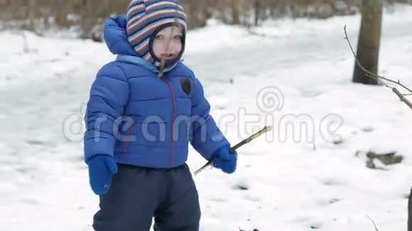 冬天森林里一个迷人的孩子看镜头的肖像穿着蓝色夹克和深色衣服的儿童运动视频的预览图
