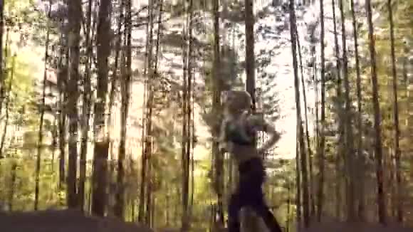 参加晨跑的女运动员日出时一个肌肉发达的女孩在阳光下爬上山坡视频的预览图