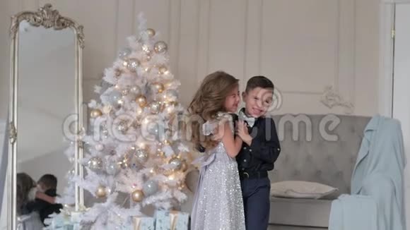 男孩和女孩在圣诞树背景上特写穿着漂亮衣服的孩子视频的预览图