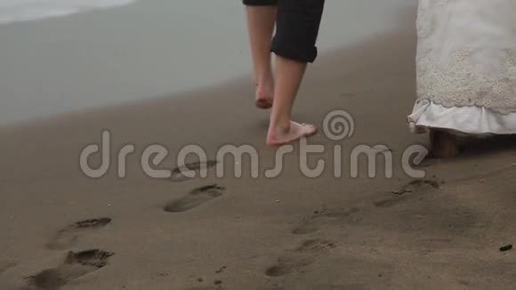 新婚夫妇手牵着手在沙滩上留下足迹视频的预览图