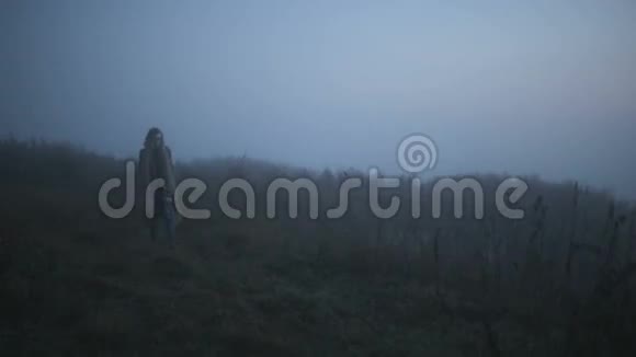 穿着长围巾的女孩在雾中徘徊视频的预览图