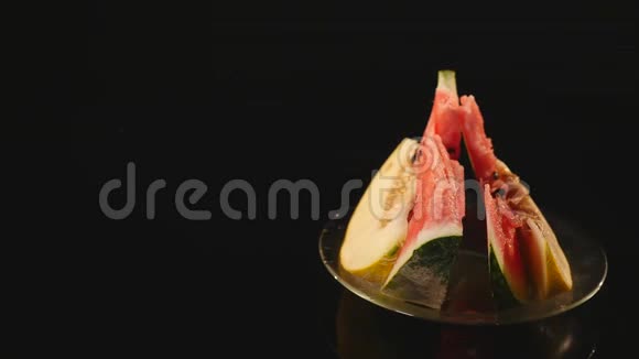 在黑色背景上旋转的盘子上的多汁的成熟西瓜和甜瓜视频的预览图