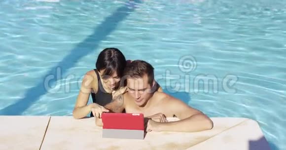 游泳池的微笑情侣使用数字设备视频的预览图