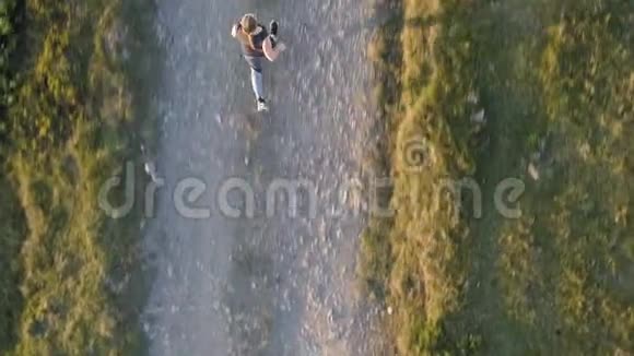 日落时在乡村路上奔跑的女人视频的预览图