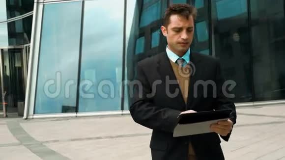 商人在大楼外使用电子平板电脑视频的预览图