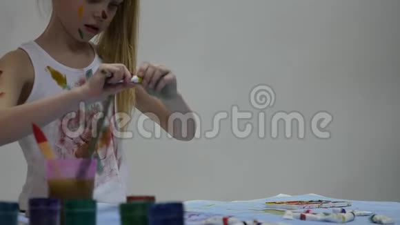 小女生可爱的小女孩画家在桌子上画画在她的衣服上画画慢动作视频的预览图