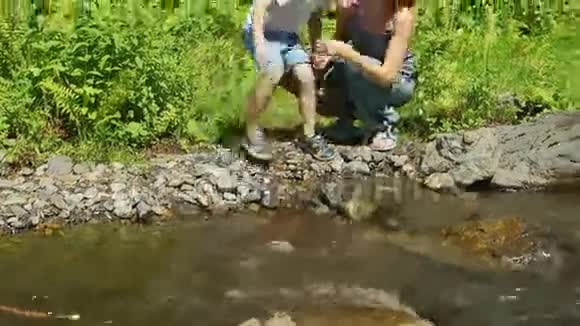 母亲和儿子的肖像坐在小溪旁视频的预览图