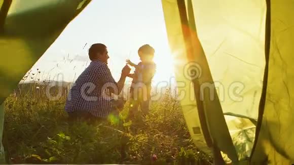 父亲和他的儿子在日落时在旅游帐篷附近玩耍从帐篷看风景视频的预览图
