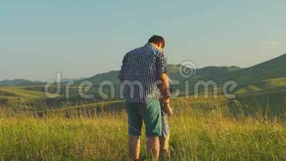 父亲抱着儿子在风景优美的背景下转悠视频的预览图