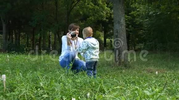 妈妈在一个夏天的公园里用复古摄像机拍摄她的小男孩视频的预览图