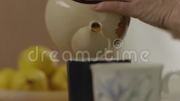 女人的手把茶壶里的茶倒进杯子里视频的预览图