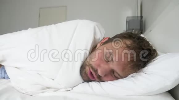 生病的年轻人发烧睡在床上被毯子盖着视频的预览图