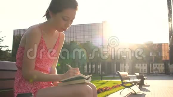 女孩在日落时分在阳光下做笔记把她对未来的希望和梦想写在日记里制定计划视频的预览图