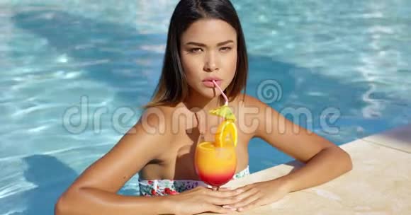 一位严肃的年轻女士喝着橙色朗姆酒鸡尾酒视频的预览图