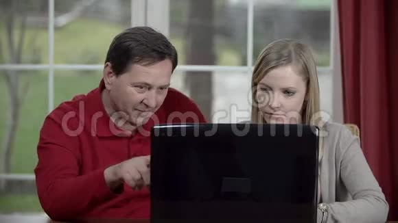 父亲帮助女儿使用个人电脑视频的预览图