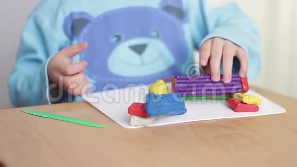 儿童的手臂在桌上用橡皮泥雕刻图形视频的预览图