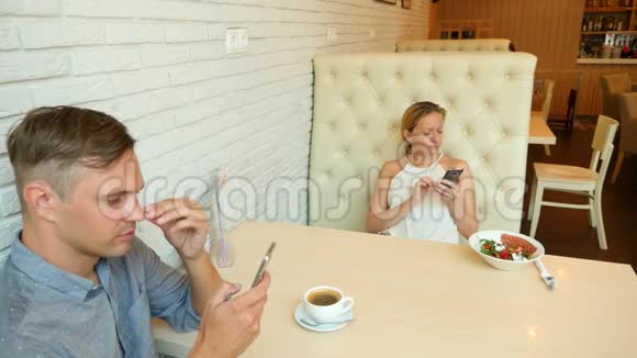 一对在咖啡馆男人和美女约会每个人都在看他的手机4k慢动作视频的预览图