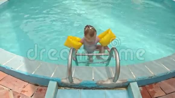小女孩带着梯子从泳池来到泳池边视频的预览图
