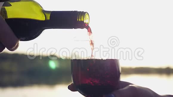 在大海的背景上倒入一杯昂贵的葡萄酒其中有反射和镜头的效果慢动作视频的预览图