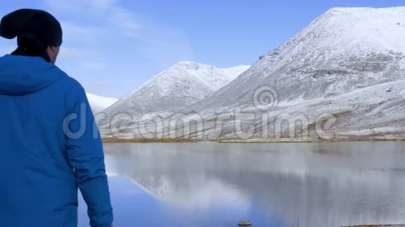 一个人站在山上的高处欣赏着美丽的景色它周围有山峰和美丽的视频的预览图