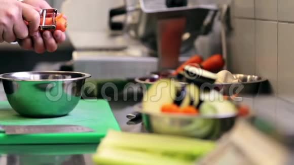 男厨师的手在厨房里做削胡萝卜视频的预览图