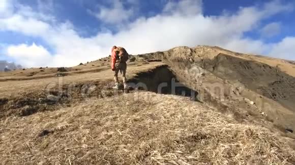 快乐的旅行女孩摄影师带着相机和背包在白雪皑皑的背景下上山视频的预览图