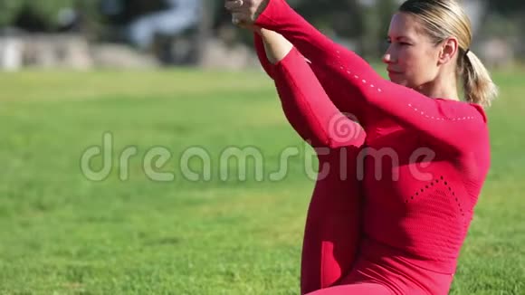 穿着红色乳胶服装的金发女郎正在做瑜伽练习视频的预览图